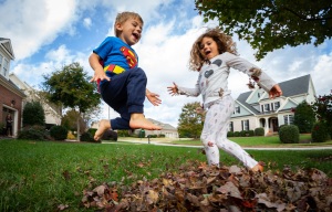 Children jump in leaves during a family portrait session